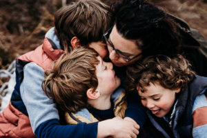 boys hugging mother during Surrey family photoshoot Ockham common
